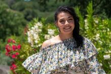 Catarina Manique sorri com vestido floral em cenário natural.
