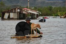 Homem e cão num barco improvisado durante as cheias