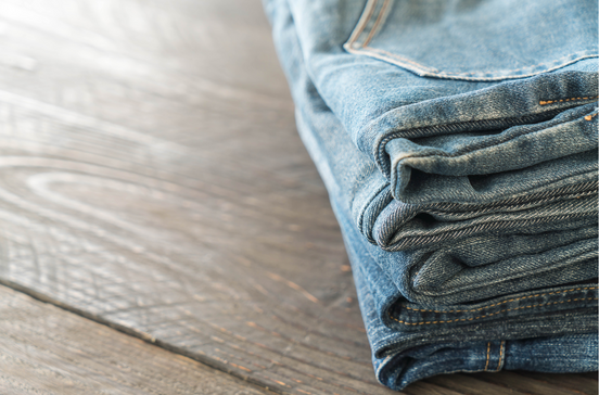 Calças de ganga empilhadas numa superfície de madeira