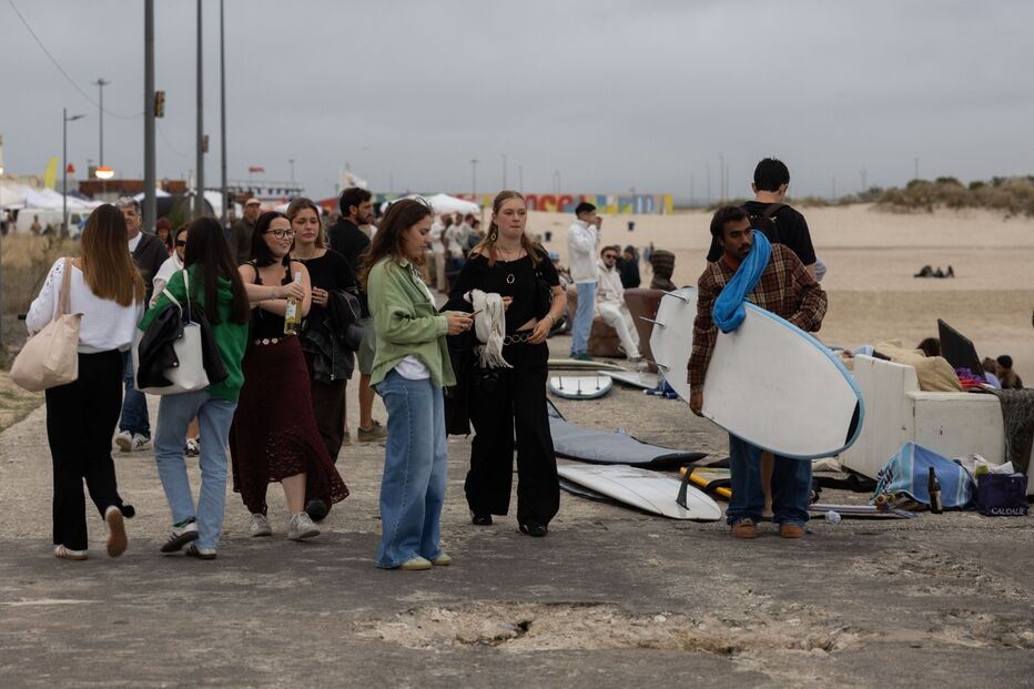 Pessoas na praia com pranchas de surf e bebidas