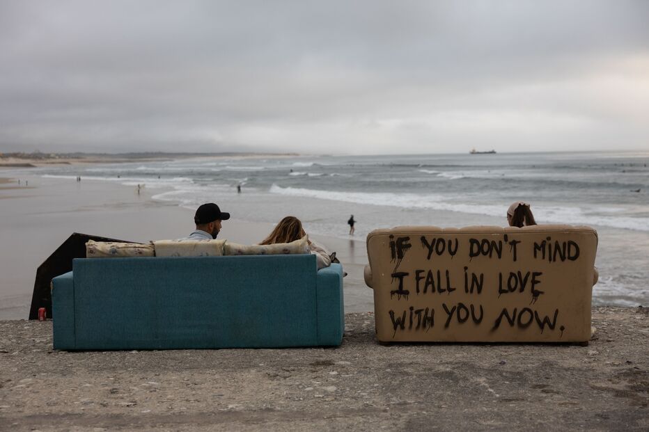 Praia com vista para o mar e sofás com mensagem de amor
