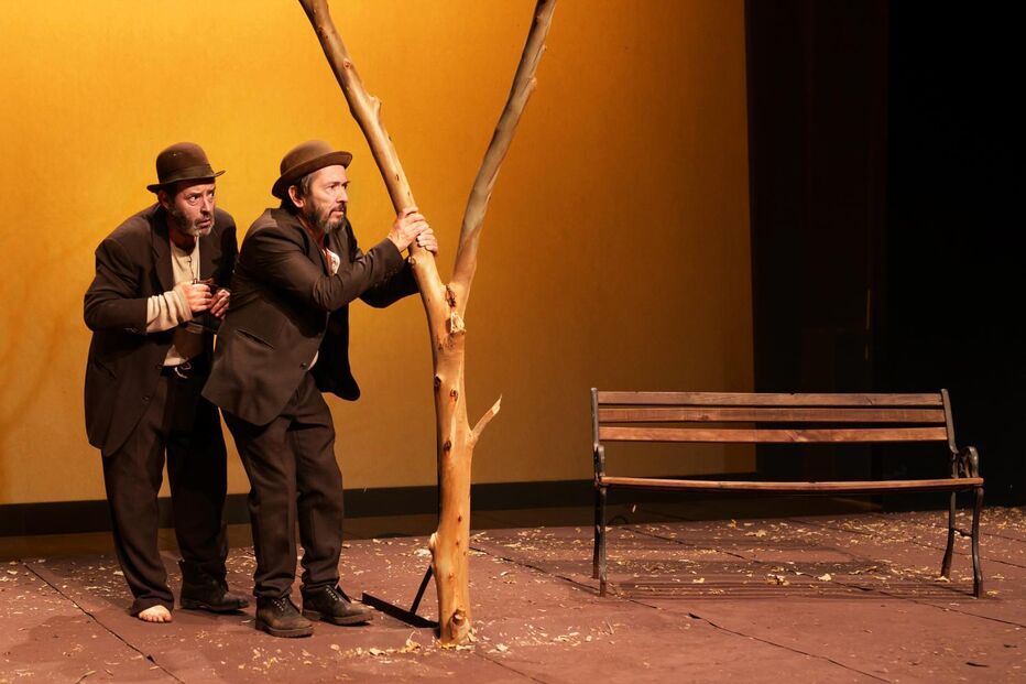 Interpretação da peça com dois homens e um banco em palco