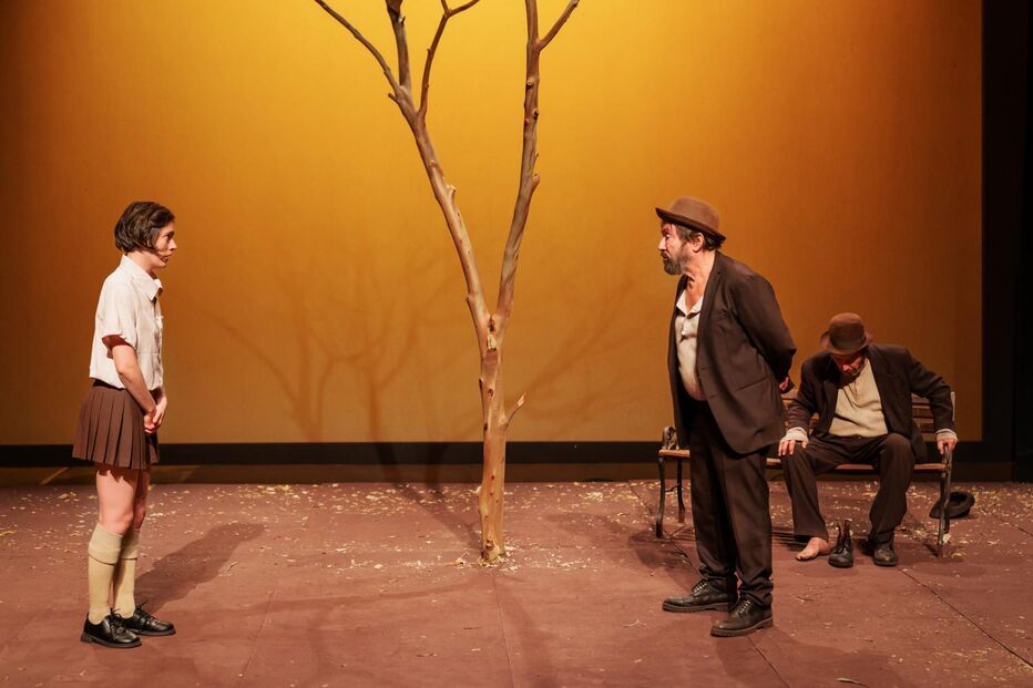 Espetáculo teatral com três atores e uma árvore no centro do palco