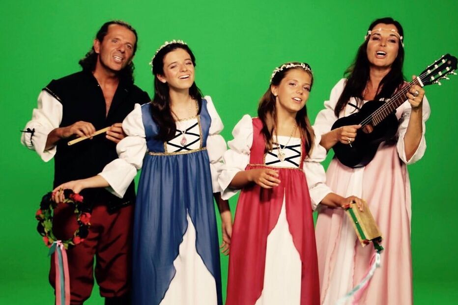 Grupo musical traja vestes medievais num cenário verde