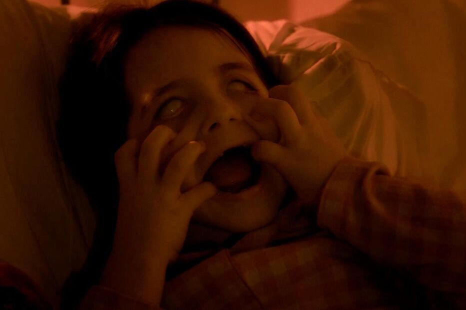 Criança assustada na cama com olhos brancos e boca aberta