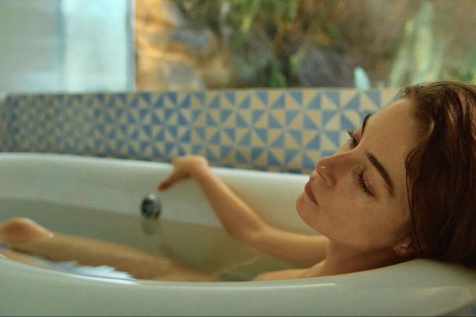 Mulher relaxa numa banheira com azulejos azuis e brancos