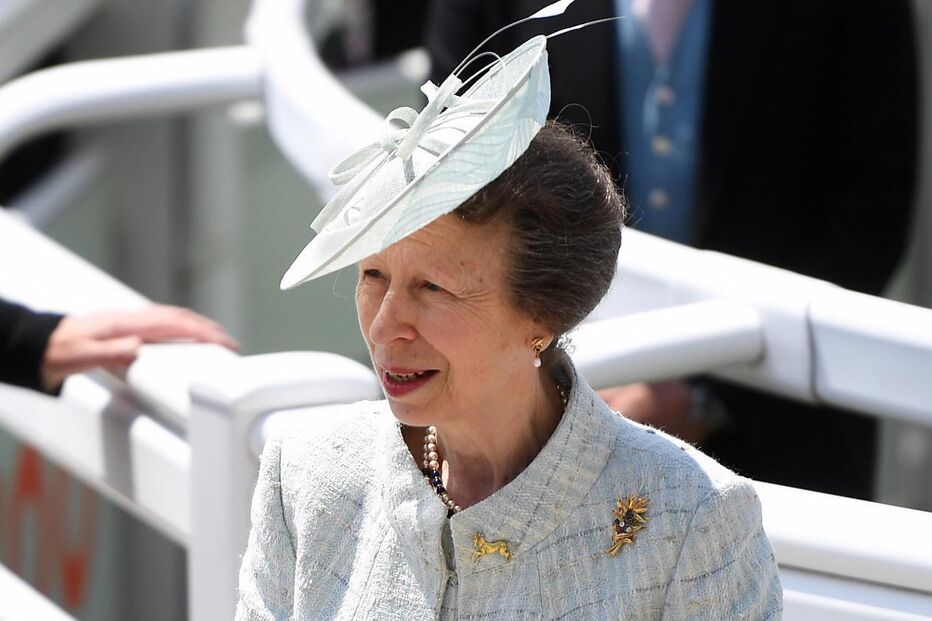 A princesa Ana num evento com um fato azul e um chapéu.
