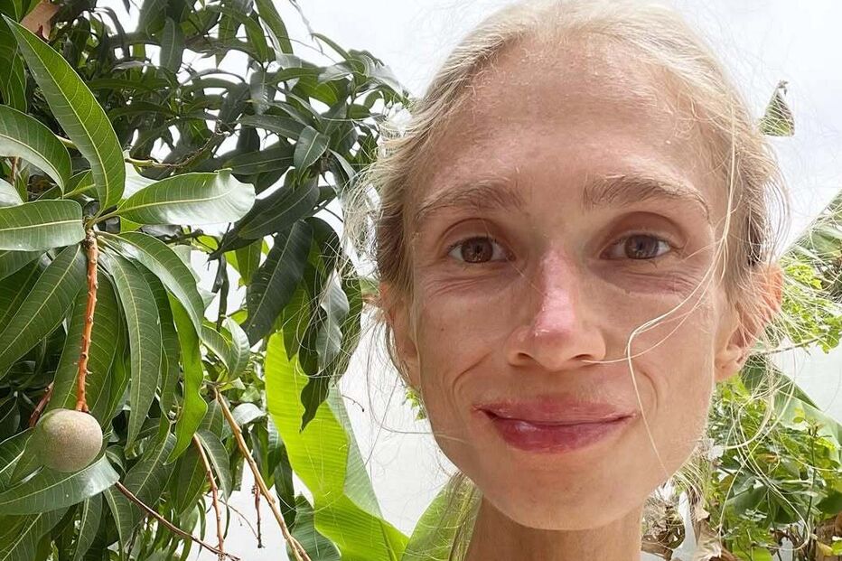 Mulher sorri perto de mangueira