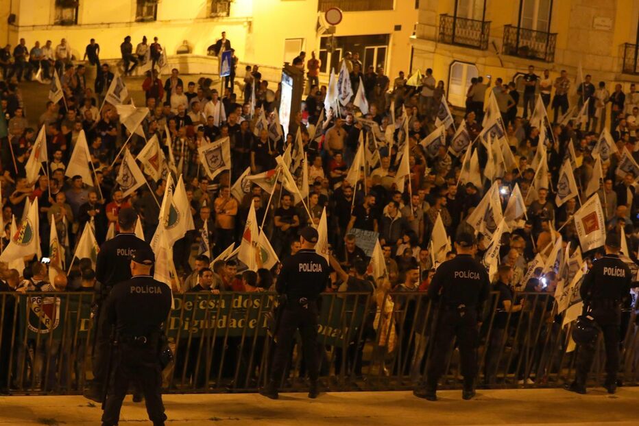 Protesto com polícia e cartazes frente a uma multidão