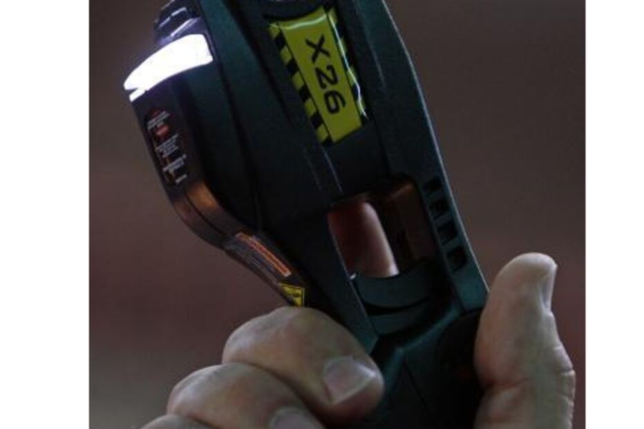 Mão segura uma arma Taser X26