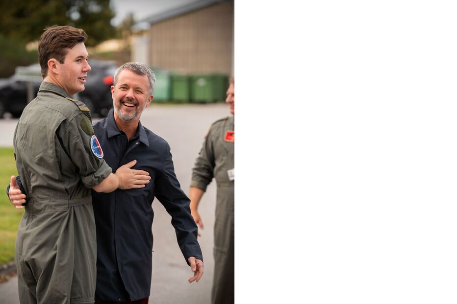 Frederico da Dinamarca abraça um piloto militar sorrindo