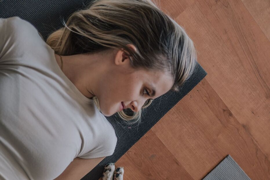 Mulher relaxa na esteira de ioga com dois cães