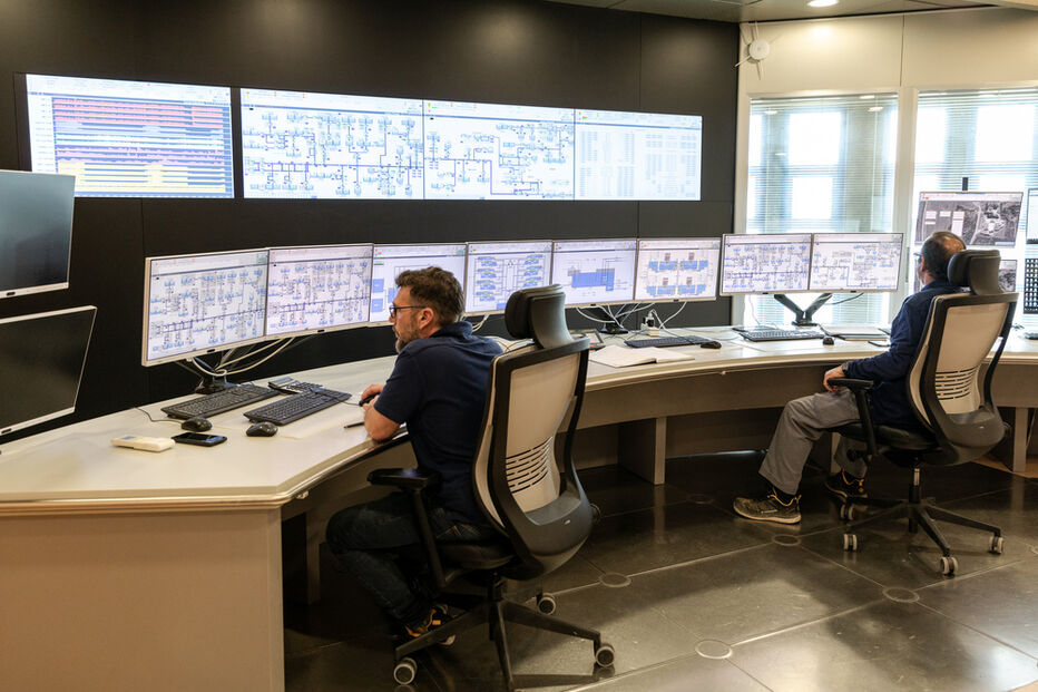 Homens monitorizam dados em computadores numa sala de controlo