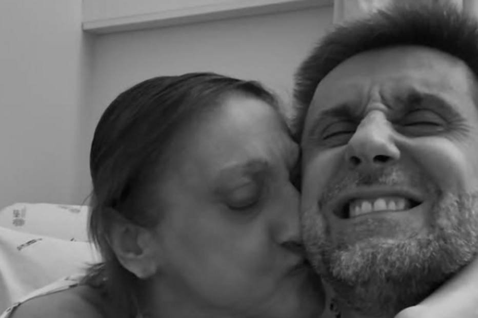 Mulher beija homem sorrindo num hospital