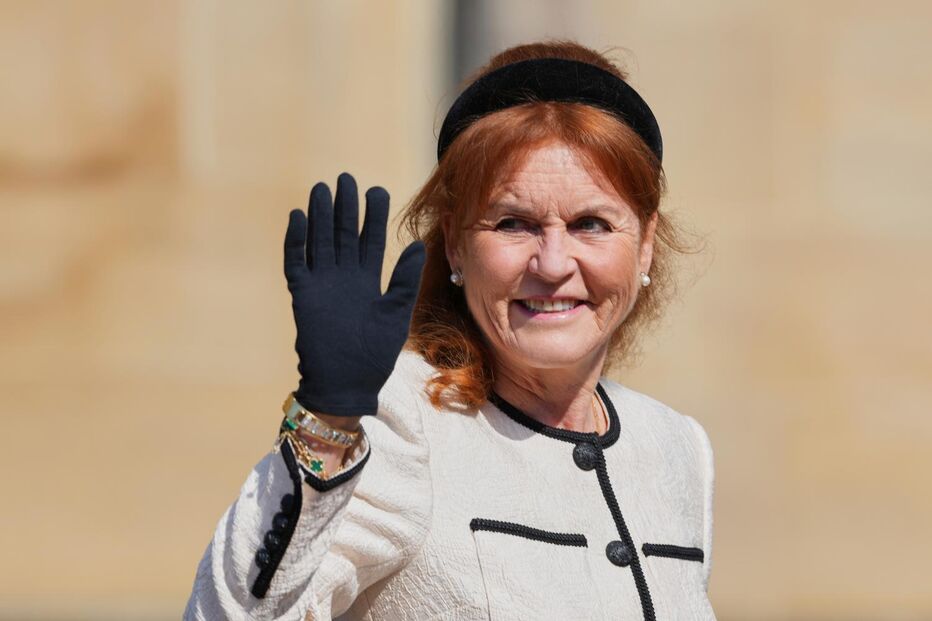 Sarah Ferguson sorri e acena com uma luva preta