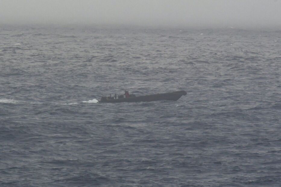 Embarcação navega em mar agitado sob céu enevoado