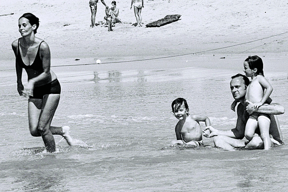 Família Kennedy nada na praia: um legado de união e esperança.

