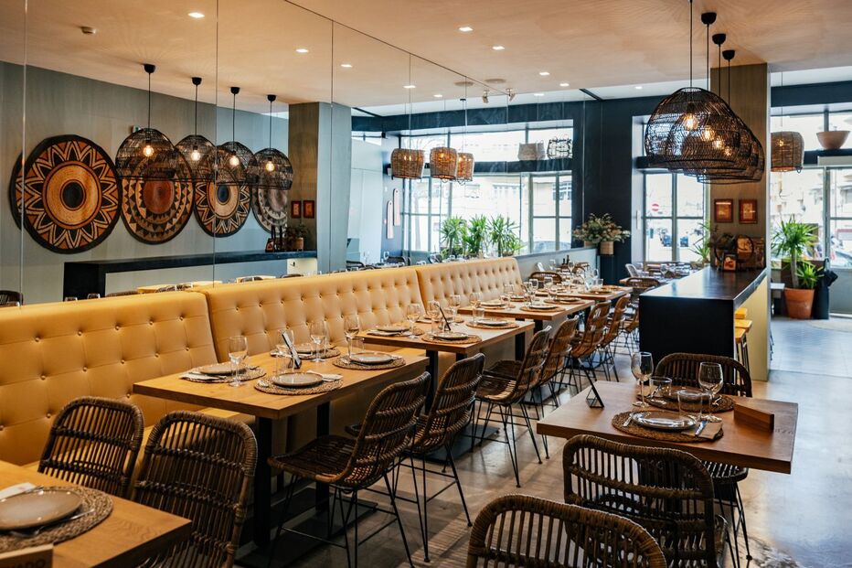 Interior de restaurante com mesas postas e cadeiras de vime