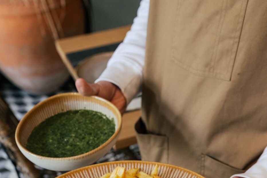 Prato com bife, molho, pimenta rosa e batatas fritas, servido por um empregado de mesa