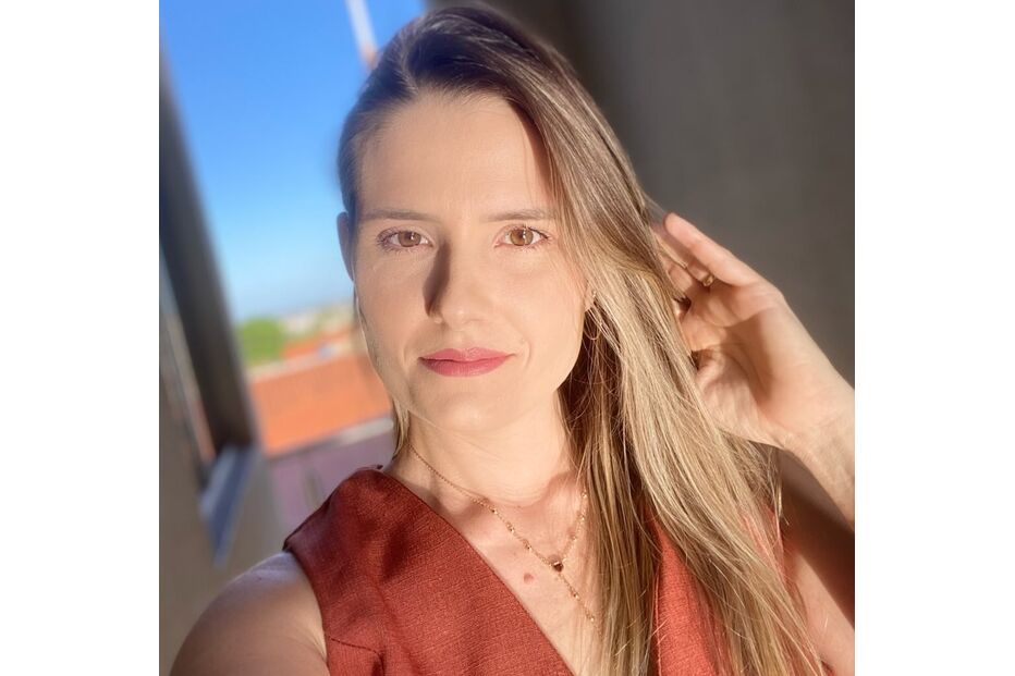Mulher posa com um vestido castanho e um colar, sob a luz solar