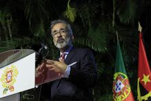 Oficial discursa ao lado das bandeiras de Portugal e Angola