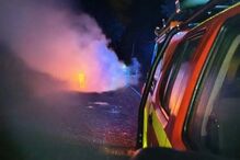 Incêndio com fumo perto de veículo de emergência em noite escura