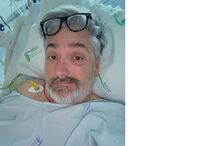 Homem de óculos numa cama de hospital com equipamento médico