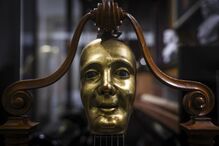 Máscara dourada com suporte de madeira num cenário desfocado