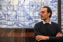 Homem posa junto a painel de azulejos em tons de azul e branco