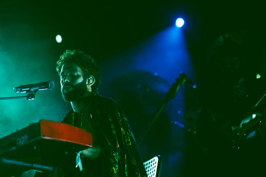 Músico atua ao piano sob luzes vibrantes em palco