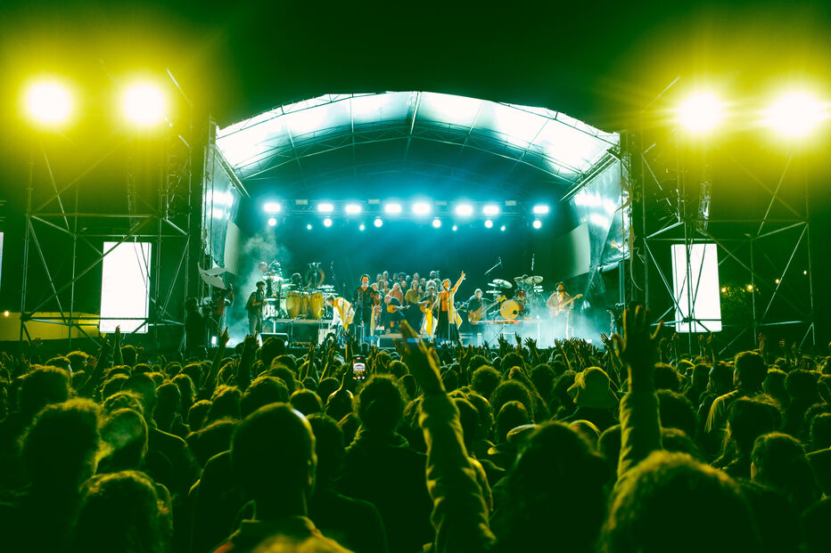 Multidão vibra com a banda em palco num concerto ao ar livre