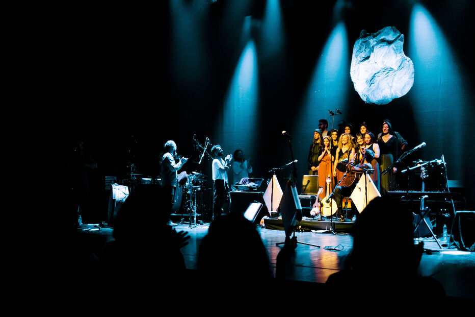 Espetáculo musical com banda e cantores num palco iluminado