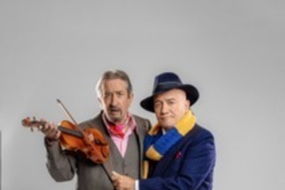 Dois homens posam: um segura um violino, outro usa fato azul e cachecol