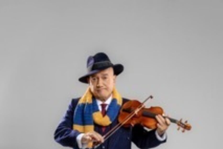 Homem com cachecol toca violino, trajando fato e chapéu