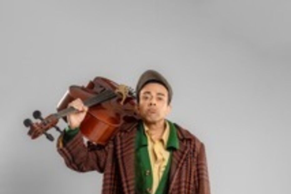 Homem posa com violino ao ombro, vestido com roupa clássica