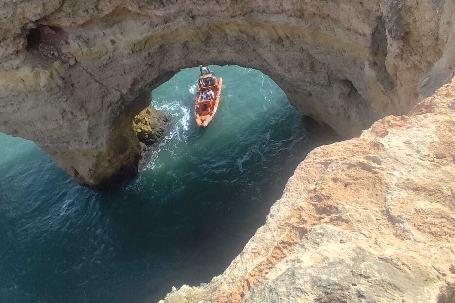 Barco navega por arco rochoso na costa do Algarve