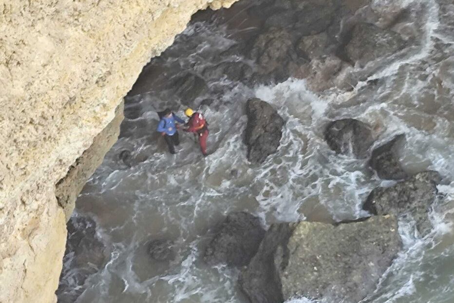 Equipa de resgate atua junto a uma falésia e resgata pessoa no mar