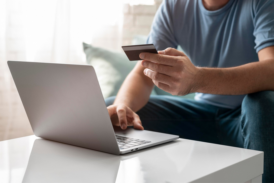 Compras online: pessoa usa cartão e portátil para aceder a descontos para o lar