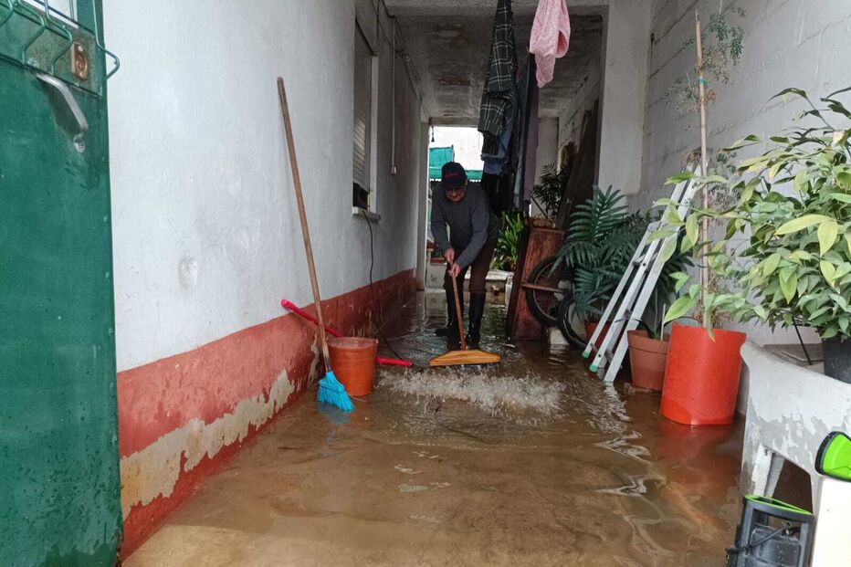 Homem tenta limpar água parada num pátio alagado