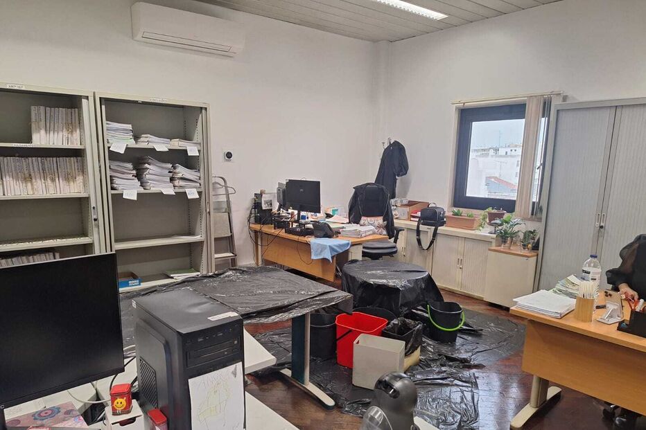 Escritório inundado com documentos e equipamentos cobertos com plástico