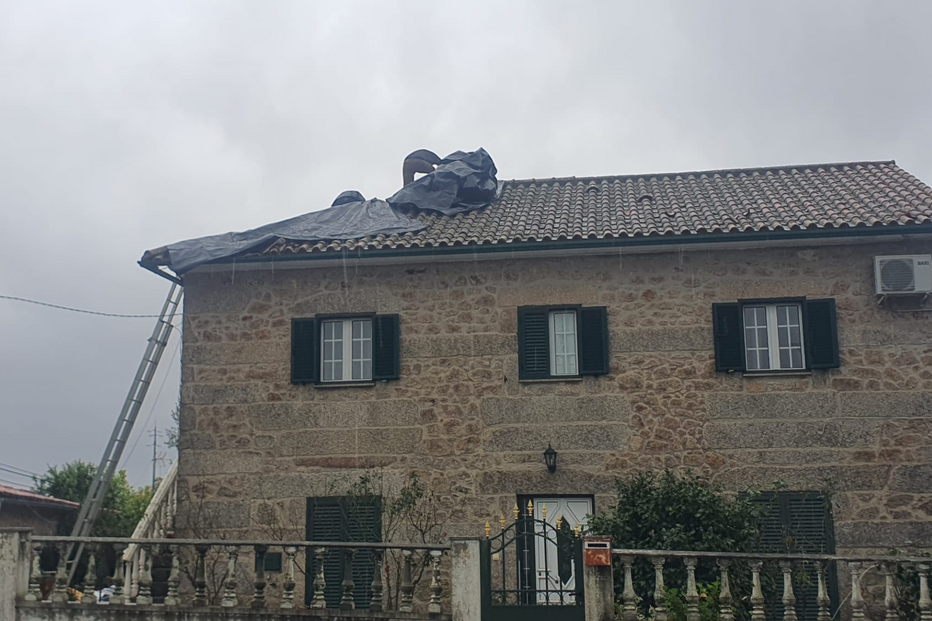 Reparação de telhado com recurso a lona e escada numa casa em pedra