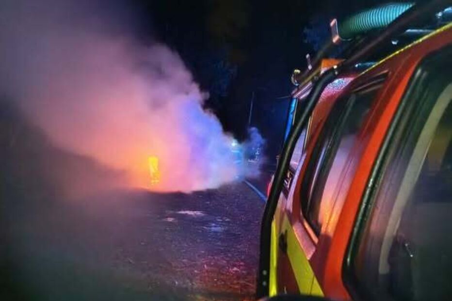 Incêndio com fumo perto de veículo de emergência em noite escura