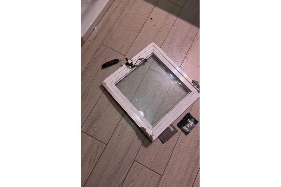 Porta de duche danificada no chão da casa de banho.
