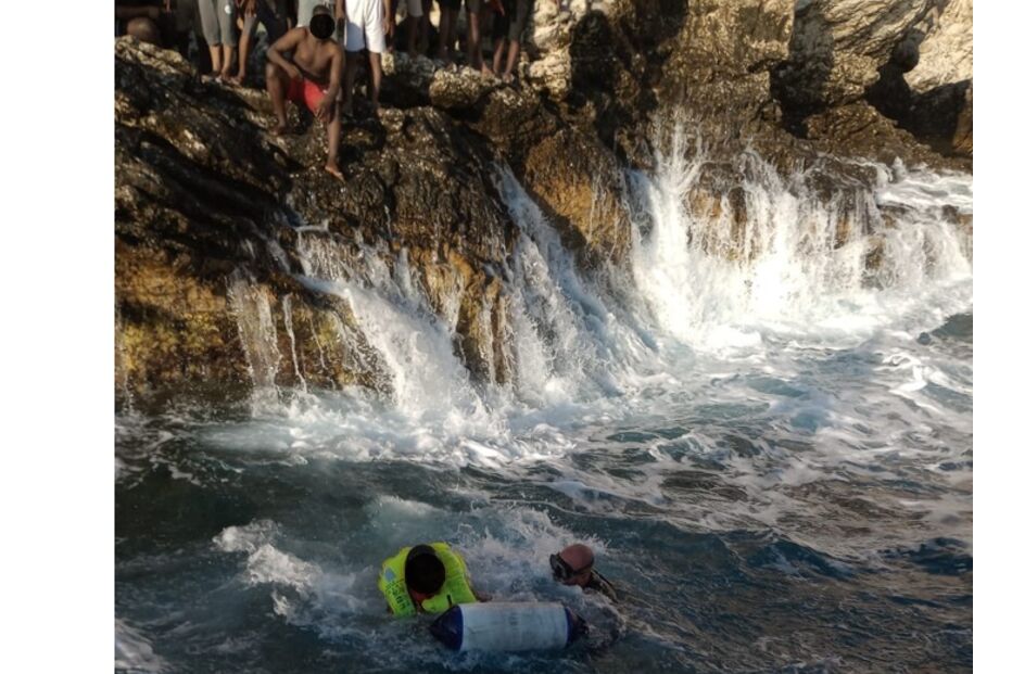 Mergulhadores em ação no mar, perto da costa rochosa