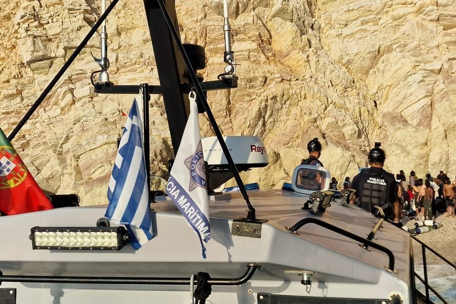 Guarda costeira com migrantes numa praia grega