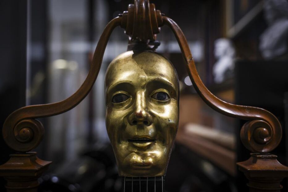 Máscara dourada com suporte de madeira num cenário desfocado