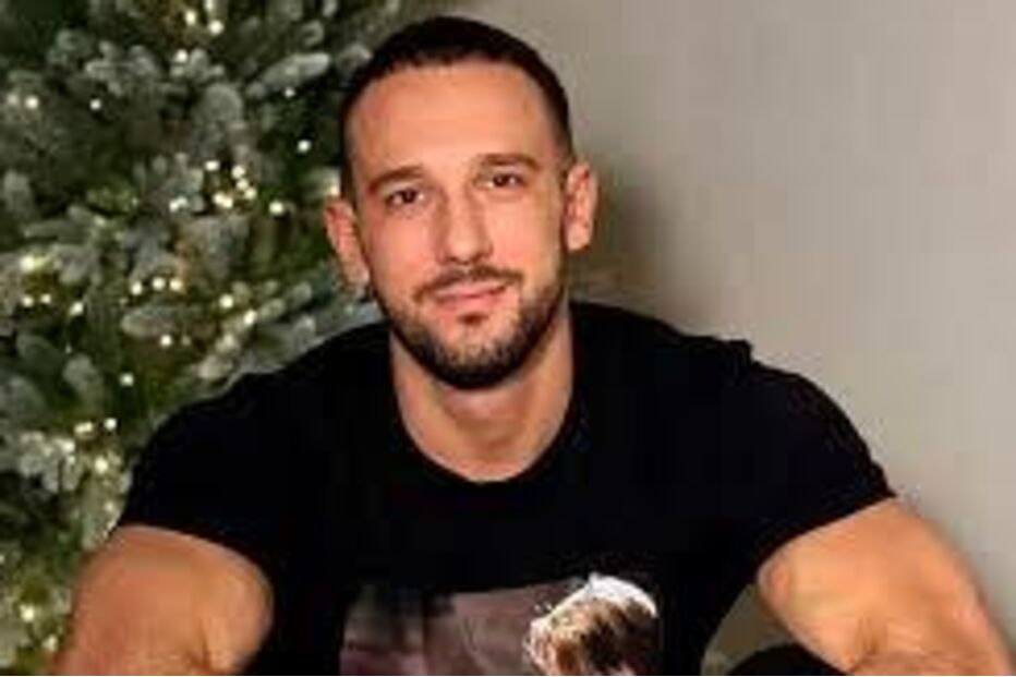 Homem sorri para a câmara junto a uma árvore decorada