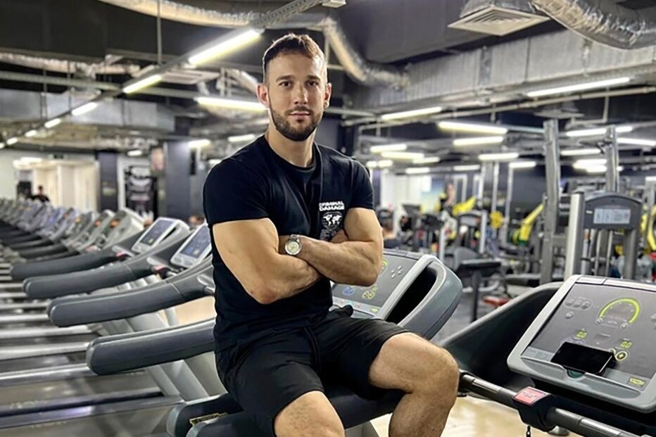 Homem posa na passadeira num ginásio, com roupa desportiva