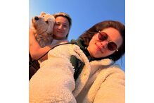 Selfie de duas pessoas e um cão com céu azul de fundo