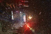 Multidão reúne-se num evento noturno iluminado por luzes e palcos